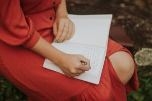 Woman sitting down and writing in her journal.