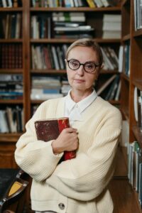 Older woman with journal clutched in arms in a library.